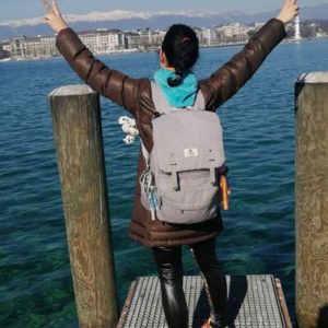 Mujer con mochila en el lago celebrando